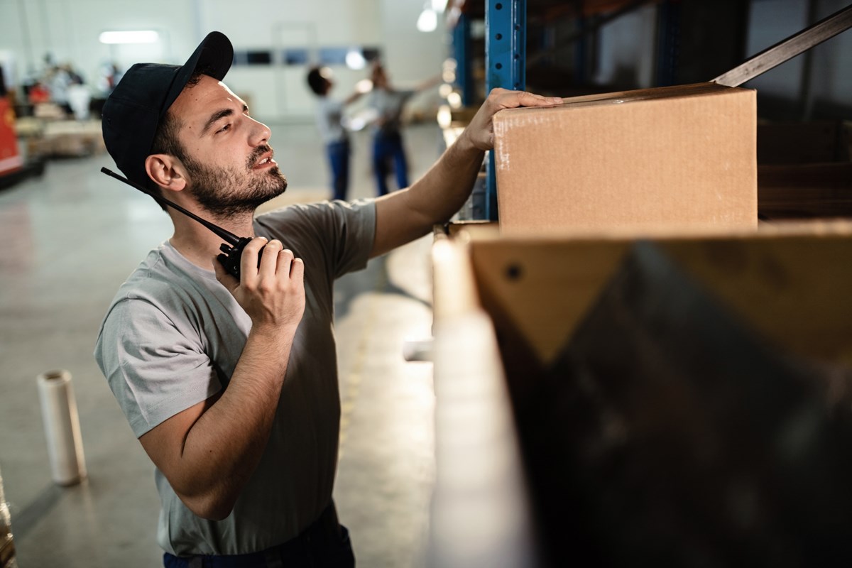 warehouse-worker-checking-packages-shipment-using-walkietalkie-industrial-storage-compartment